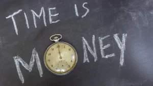 Blackboard with the words time is money and a clock instead of the 'O'