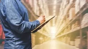 Manager in warehouse ticking off checklist
